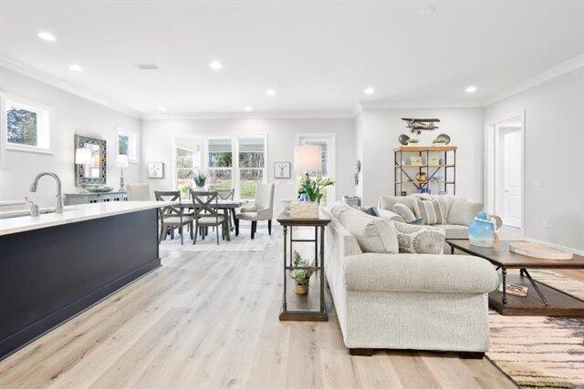 living area with recessed lighting, light wood finished floors, and ornamental molding