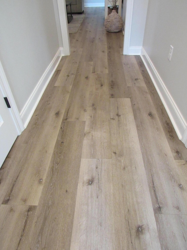 hall featuring baseboards and wood finished floors