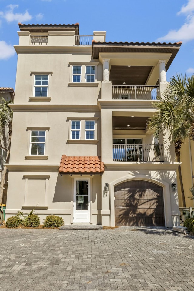 view of front facade featuring stucco siding, an attached garage, and decorative driveway