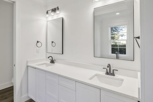 bathroom featuring double vanity, toilet, baseboards, and a sink