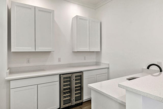 kitchen featuring dark wood-type flooring, beverage cooler, white cabinetry, a peninsula, and light stone countertops