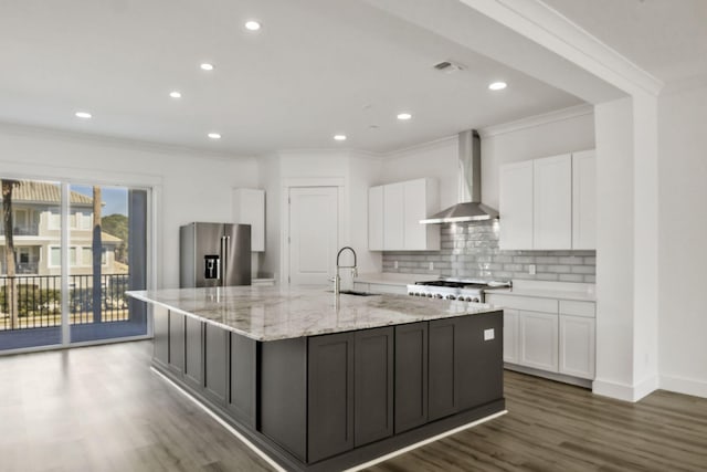 kitchen featuring ornamental molding, white cabinets, wall chimney exhaust hood, stainless steel fridge, and backsplash