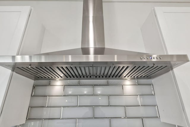 details with white cabinets and wall chimney exhaust hood