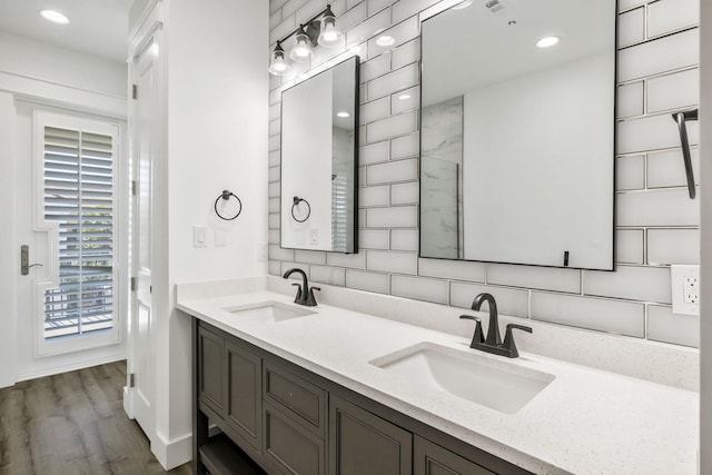 bathroom featuring double vanity, wood finished floors, tasteful backsplash, and a sink