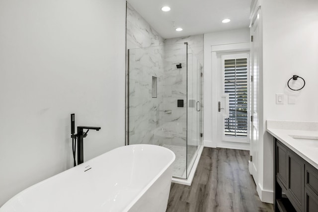 full bathroom with a marble finish shower, a freestanding tub, vanity, and wood finished floors