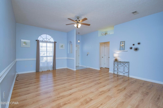 interior space featuring ceiling fan, arched walkways, visible vents, and light wood-type flooring