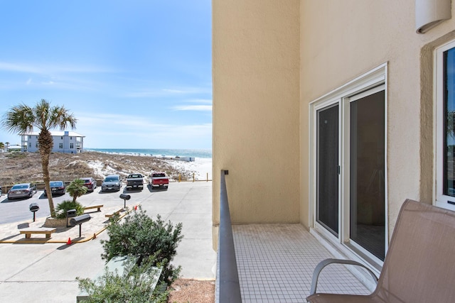 balcony featuring a view of the beach and a water view