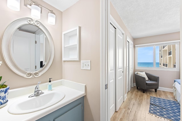 bathroom with baseboards, a textured ceiling, wood finished floors, and vanity