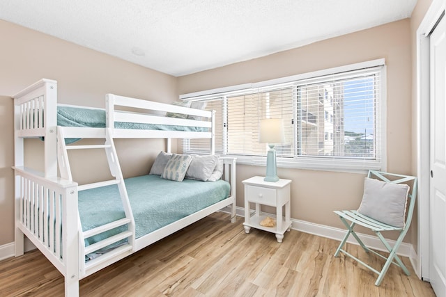 bedroom with baseboards, a textured ceiling, and wood finished floors