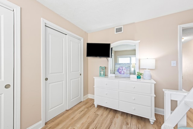 bedroom featuring visible vents, baseboards, a textured ceiling, and light wood-style flooring