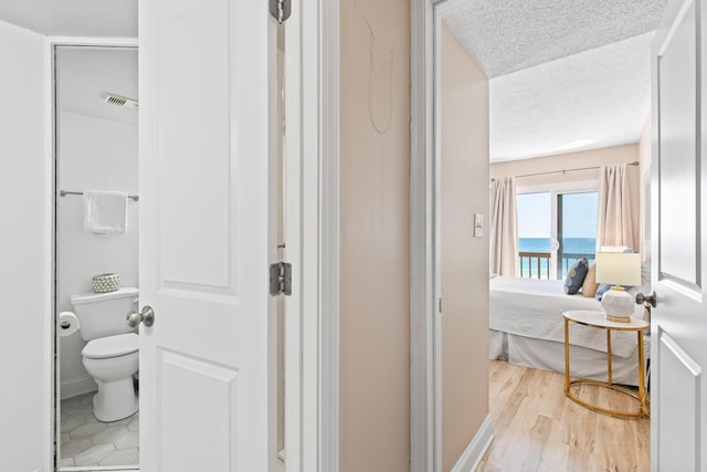 ensuite bathroom featuring visible vents, toilet, ensuite bathroom, wood finished floors, and a textured ceiling