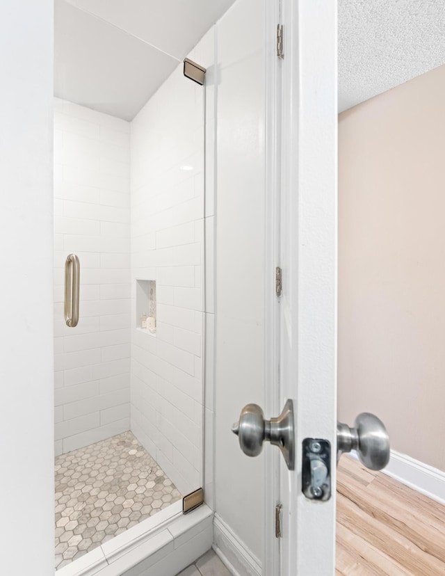 full bathroom featuring a shower stall, baseboards, and a textured ceiling