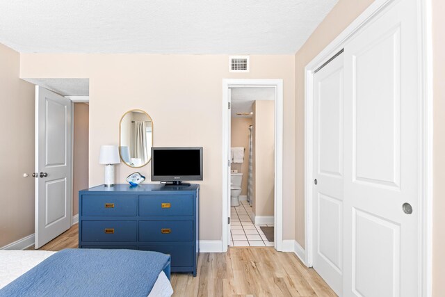 bedroom with visible vents, light wood-style flooring, a textured ceiling, a closet, and baseboards