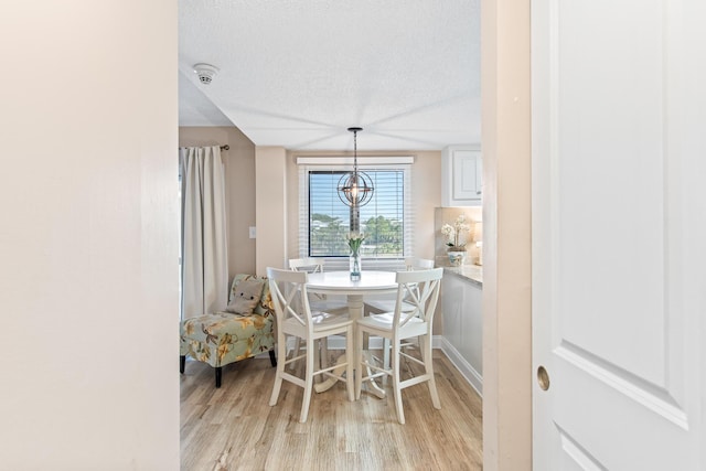 dining area with a notable chandelier, a textured ceiling, and light wood-style flooring