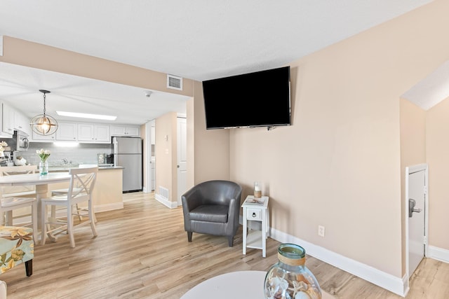 living area featuring visible vents, baseboards, and light wood-style floors