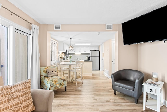 living area with light wood-type flooring and visible vents