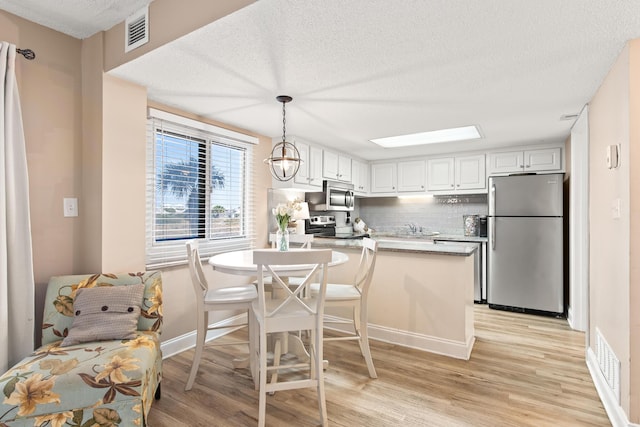 kitchen with backsplash, visible vents, light wood finished floors, and stainless steel appliances