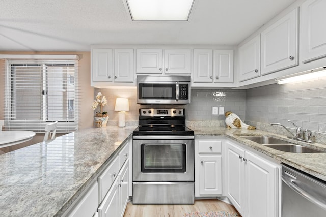 kitchen featuring light wood-style flooring, appliances with stainless steel finishes, white cabinets, and a sink