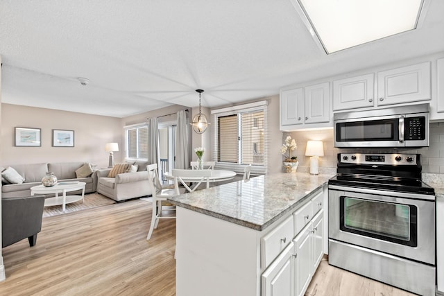 kitchen with open floor plan, light wood-type flooring, a peninsula, white cabinets, and stainless steel appliances