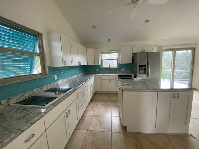 kitchen featuring stainless steel refrigerator with ice dispenser, a sink, tasteful backsplash, a kitchen island, and vaulted ceiling