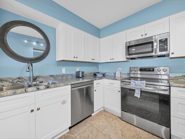 kitchen featuring stainless steel appliances, light stone countertops, white cabinetry, and a sink