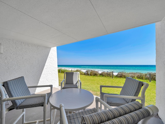balcony with a water view, outdoor dining space, and a view of the beach
