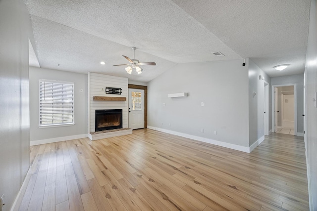 unfurnished living room featuring vaulted ceiling, visible vents, light wood-type flooring, and a large fireplace