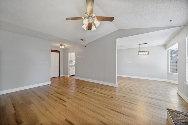 unfurnished living room with light wood-type flooring, baseboards, ceiling fan, and vaulted ceiling