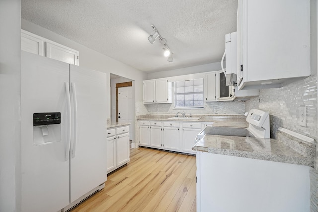 kitchen featuring white appliances, light wood-style flooring, light countertops, white cabinetry, and tasteful backsplash