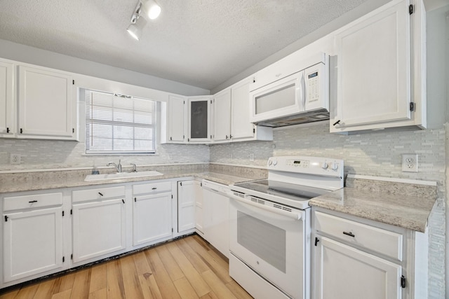 kitchen featuring white appliances, light wood-style flooring, a sink, decorative backsplash, and white cabinetry