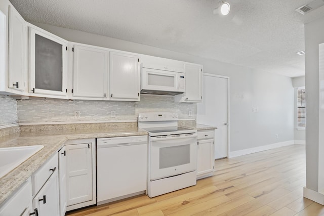 kitchen with white appliances, visible vents, light wood-type flooring, white cabinetry, and tasteful backsplash