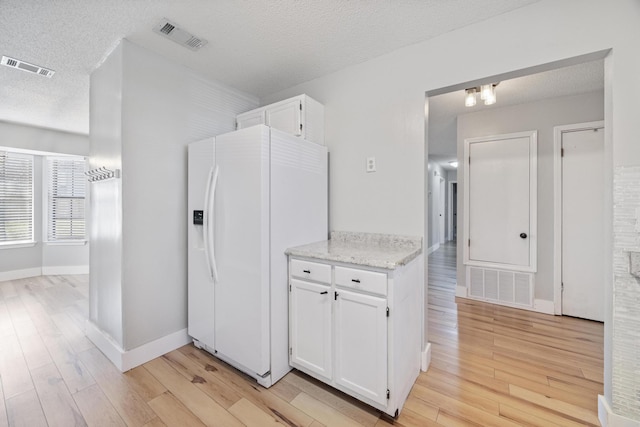 kitchen with visible vents, white fridge with ice dispenser, and light wood-style flooring