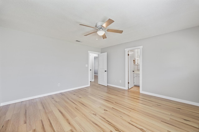 empty room featuring baseboards, light wood-style floors, ceiling fan, and a textured ceiling