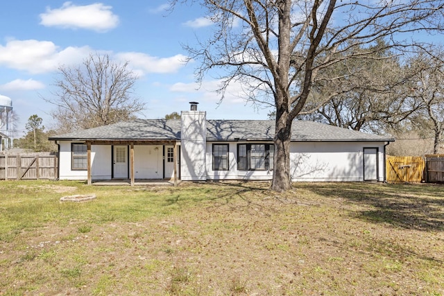 back of house with a patio, a lawn, a chimney, and fence