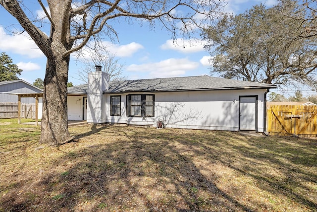 back of property with fence, a lawn, and a chimney