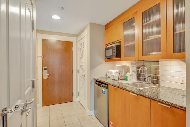 kitchen featuring light tile patterned floors, light stone countertops, a sink, stainless steel dishwasher, and backsplash