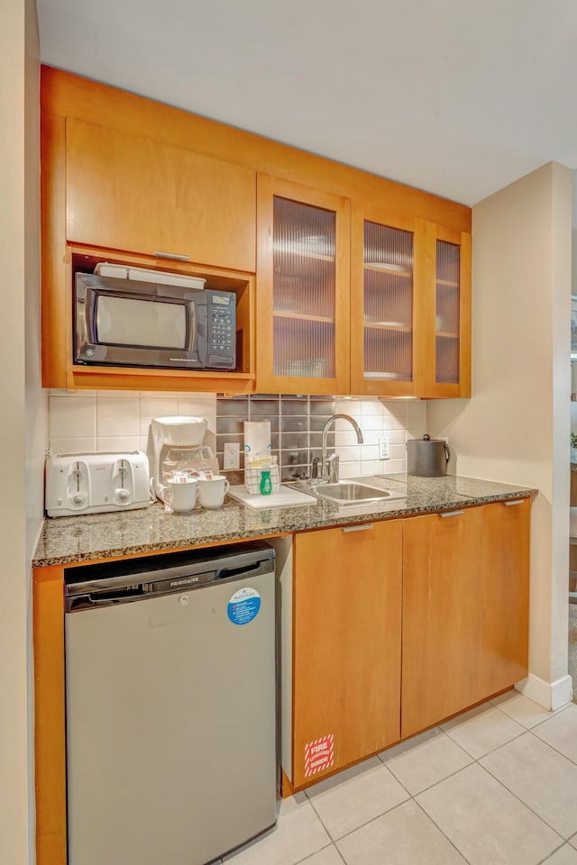 kitchen featuring a sink, backsplash, refrigerator, and black microwave