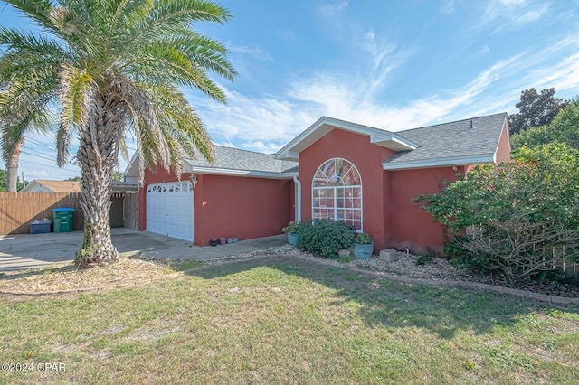 view of front of property with fence, driveway, stucco siding, a front lawn, and a garage