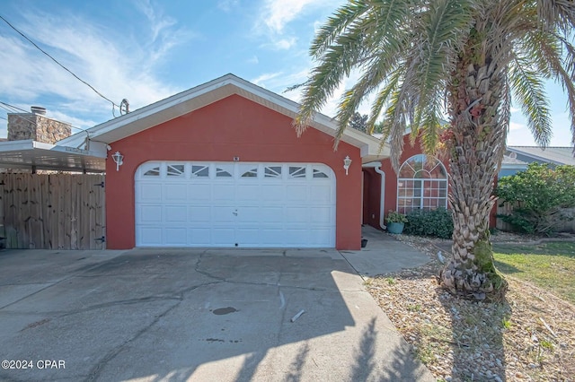 view of front of home featuring stucco siding, driveway, an attached garage, and fence