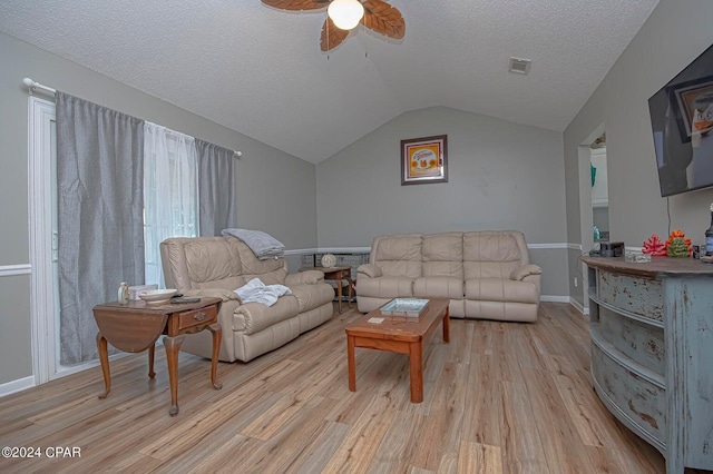 living area featuring vaulted ceiling, visible vents, light wood finished floors, and a textured ceiling