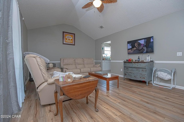 living room featuring visible vents, lofted ceiling, ceiling fan, a textured ceiling, and light wood-type flooring