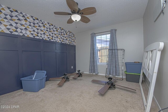 exercise area featuring carpet floors, a textured ceiling, and ceiling fan