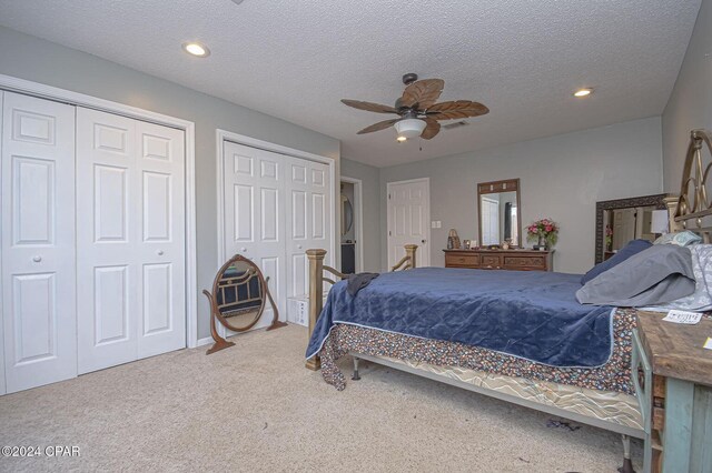 bedroom featuring a ceiling fan, recessed lighting, multiple closets, a textured ceiling, and carpet flooring