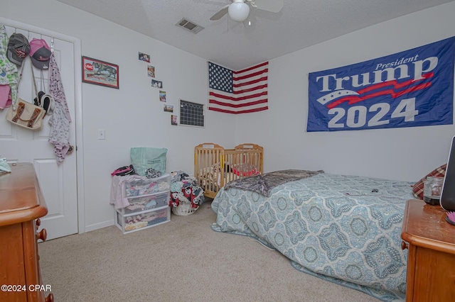 bedroom with ceiling fan, carpet, visible vents, and a textured ceiling