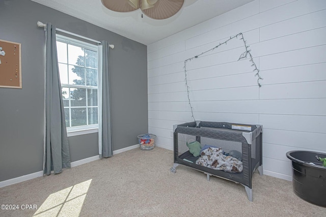 interior space with baseboards, wooden walls, and a ceiling fan