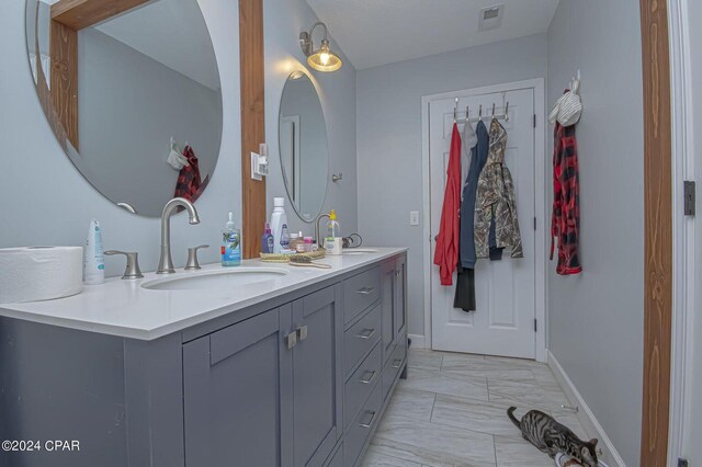 full bath with double vanity, visible vents, marble finish floor, and a sink