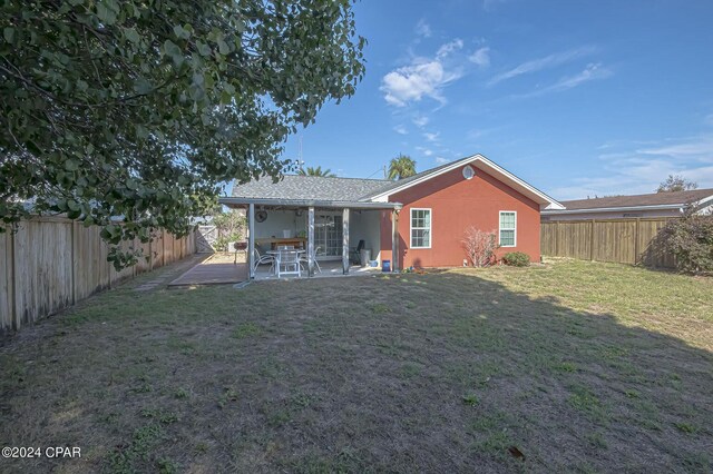 rear view of property featuring a fenced backyard, a lawn, a patio, and stucco siding