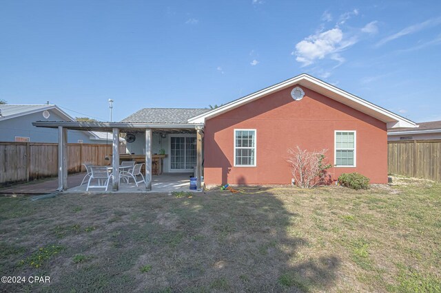 rear view of property featuring a patio, a yard, a fenced backyard, and stucco siding