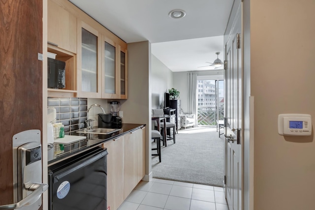 kitchen featuring light carpet, a sink, dark countertops, black microwave, and dishwashing machine