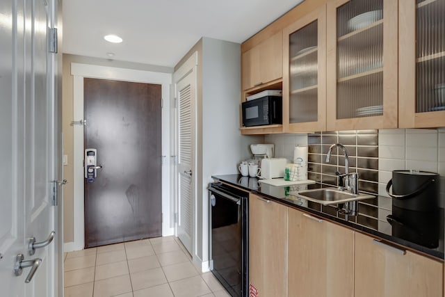 kitchen featuring a sink, dark countertops, black appliances, and light brown cabinetry